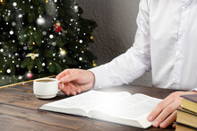 Open Bible Book On The Table. Christmas Tree. New Year. A Man In A White Shirt Sits At The Table. Prayer.
