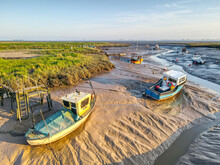 Small Fishing Boats Moored At Low Tide At Stone Creek Inlet, Sunk Island, East Yorkshire, UK