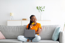 Young African American Woman Buying Online With Credit Card And Laptop, Sitting On Couch At Home, Copy Space