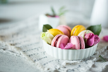 Wall Mural - Good morning. Delicious macarons desserts are served on the table in the morning for breakfast. Beautiful light still life with a rose highlight. Baking for breakfast on a light table with copy space