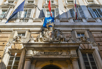 Wall Mural - Detail of the façade of Palazzo Doria-Tursi, seat of the town hall of Genoa, with the city's coat of arms, sculptures and flags, Liguria, Italy