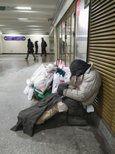 A Tramp, A Beggar, A Homeless Man With His Belongings Is Warming Himself And Sleeping At The Fan Grille In The Subway Crossing In The Winter Frost. 24.12.2021.Saint-Petersburg. Russia.  