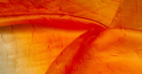 Silk fabric Orange yellow. Gradient of fabric colors. Dented and smoothed with traces of stripes. Texture background. Dupioni rainbow tangerine orange silk