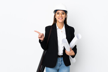 Young architect caucasian woman with helmet and holding blueprints over isolated background pointing finger to the side