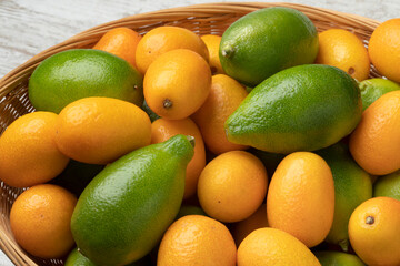 Basket with fresh green limequats and orange kumquats close up