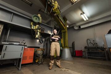 Wall Mural - Welder looking at camera near machinery in factory