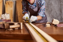 Female Craftsmen Use Tape Measure To Assemble Wooden Pieces. Construction Worker Hold Ruler. Professional Carpenter At Work Measuring Wooden Planks.