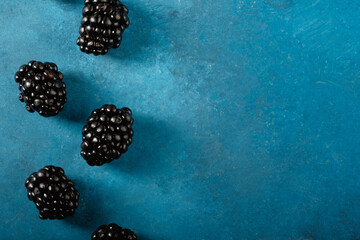 Wall Mural - Blackberry berries on blue texture background with copy space for healthy fruit food.