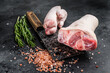 Butcher shop - Raw pork hoof,  knuckle, feet on a cutting board. Black background. Top view