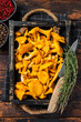 Harvested Raw Chanterelles mushrooms in a rustic tray.  Dark Wooden background. Top view