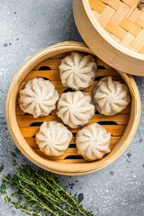 Wall Mural - Steamed baozi dumplings stuffed with meat in a bamboo steamer. Gray background. Top view