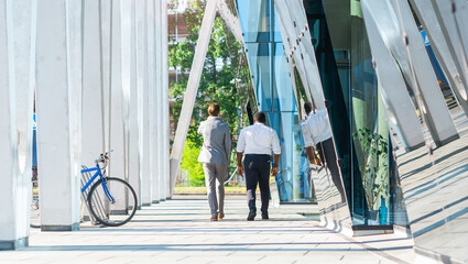 Wall Mural - Finance, business and cooperation concept. Two successful businessmen are talking on the street. Office workers are discussing business issues outdoor.