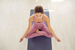 © Studio Romantic - Healthy spirit in healthy body. Happy calm serene beautiful Caucasian woman sitting in easy cross legged lotus pose on yoga mat in gym, doing meditation, enjoying moment of zen, high angle, from above