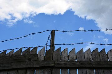 Fence with barbed wire. Caution, danger area. Forbidden fence against the sky.