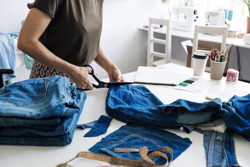 Wall Mural - Reuse, repair, upcycle. Sustainable fashion, Circular economy. Denim upcycling ideas, repair and using old jeans. Close-up of old denim jeans fabric stack in Sewing studio.