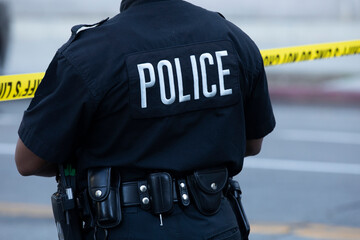 Detailed view of police uniform and cordon tape sealing off an active crime scene.