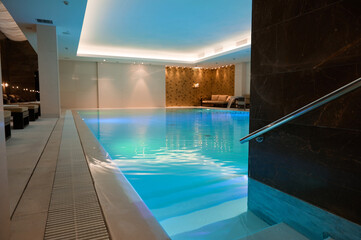 View of a luxurious modern interior design of a wellness spa resort with a thermal swimming pool with underwater lights and waterfall