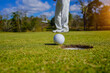 © somchai - Golf clubs and golf balls on a green lawn in a beautiful golf course with morning sunshine. golf ball on green grass ready to hit on golf course background