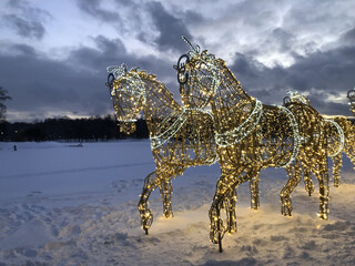 two glowing figures of galloping horses in the field.decoration of the city for the winter christmas holiday.snow and light in the park