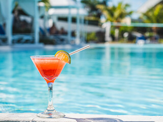 Wall Mural - Beautiful glass with a refresh cocktail and a pretty woman on the background of the swim pool. Top view, close-up. Vacation and travel concept. Moments of celebration