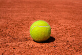 Fototapeta  - A tennis ball on a dirt court. bright sunny day. vivid colors