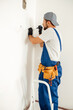 © Kostiantyn - Concentrated electrician, handyman using screwdriver while working on installing socket on wall at home