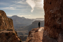 Morning Light Shines Over A Woman Hiking In The Grand Canyon