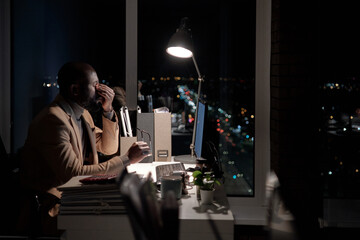 Poster - Young exhausted businessman trying to concentrate while working in front of computer in office late at night