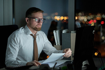 Poster - Young serious accountant in formalwear looking at computer screen while checking financial data in documents