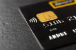 Debit card with contactless technology and chip on a black background macro. Black credit card for goods and services payment. Money cash withdrawals by bank plastic card.