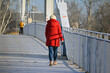 Osoba w czerwonej kurtce na Biały metalowy most zimą na niebieskim tle. 