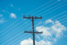 Power Lines Against A Bright Blue Cloudy Sky