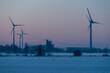 Windräder drehen sich im Industriegebiet Rothensee in Magdeburg, während die untergehende Sonne den Himmel verfärbt.