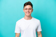 Young handsome Brazilian man isolated on blue background With glasses with happy expression