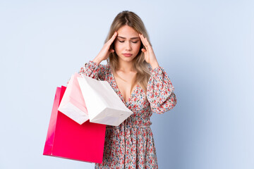 Wall Mural - Teenager Russian girl with shopping bag isolated on blue background with headache