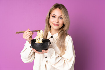 Wall Mural - Teenager Russian girl isolated on purple background holding a bowl of noodles with chopsticks