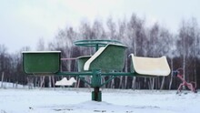 An Empty Merry-go-round At The Playground Is Spinning On A Cold Winter Day. It's Snowing A Little