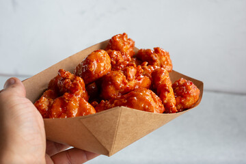 Wall Mural - A view of a hand holding a tray of glazed boneless chicken wings.