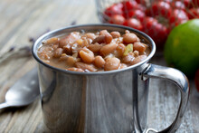 A Closeup View Of A Metal Cup Of Cooked Pinto Beans.
