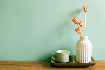 Wall Mural - Mug cup with vase of dry flowers on wooden table. mint wall background