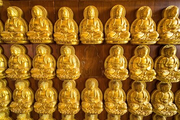 Bangkok, Thailand - December, 20, 2021 : Many golden buddha statues arrange by row and column at the wall in Wat Leng Nei Yee 2 Temple at Bangkok, Thailand.