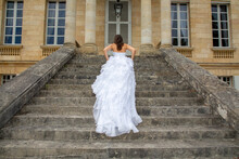 Bride Walks Up The Steps Of Town Hall On Her Wedding Day Holding Her Dress