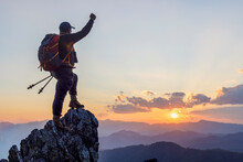 Silhouette Successful Hiker Outstretched Arms With Holding Stick On Mountain Top Cliff Edge At Sunset Background. Success People And Hiking Adventure Concept.