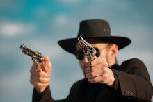 Sheriff In Black Suit And Cowboy Hat Shooting Gun, Close Up Western Portrait. Wild West, Western, Man With Vintage Pistol Revolver And Marshal Ammunition.