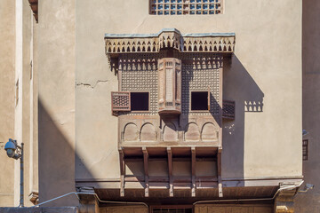 Mamluk era style oriel window covered by interleaved wooden grid - Mashrabiya, on shabby grunge external wall, at historical House of Egyptian Architecture, old Cairo, Egypt