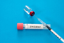 Medical Syringe In Vial With Omicron Swab Tube Against Blue Background