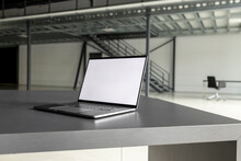 Laptop With Blank Screen At Desk In Industial Hall