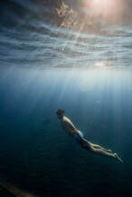 Shirtless Man Wearing Swimming Trunks Diving Undersea
