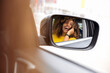 © Westend61 - Reflection of woman in side-view mirror of car