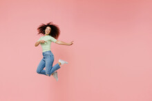 Full Size Body Length Young Curly Latin Woman 20s Wears Casual Clothes Sunglasses Jump Point Back On Workspace Area Copy Space Mock Up Isolated On Plain Pastel Light Pink Background Studio Portrait.